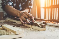 Un hombre está midiendo un trozo de madera con un lápiz.