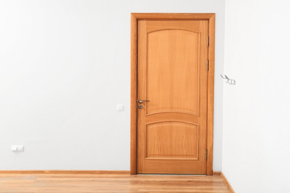 Una habitación vacía con una puerta de madera y un suelo de madera.