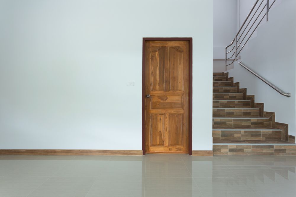 Una habitación vacía con una puerta de madera y escaleras.