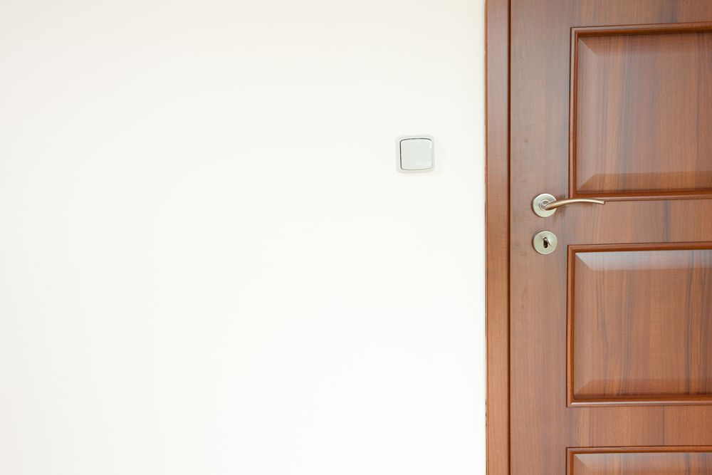 Una puerta de madera está abierta a una pared blanca en una habitación vacía.