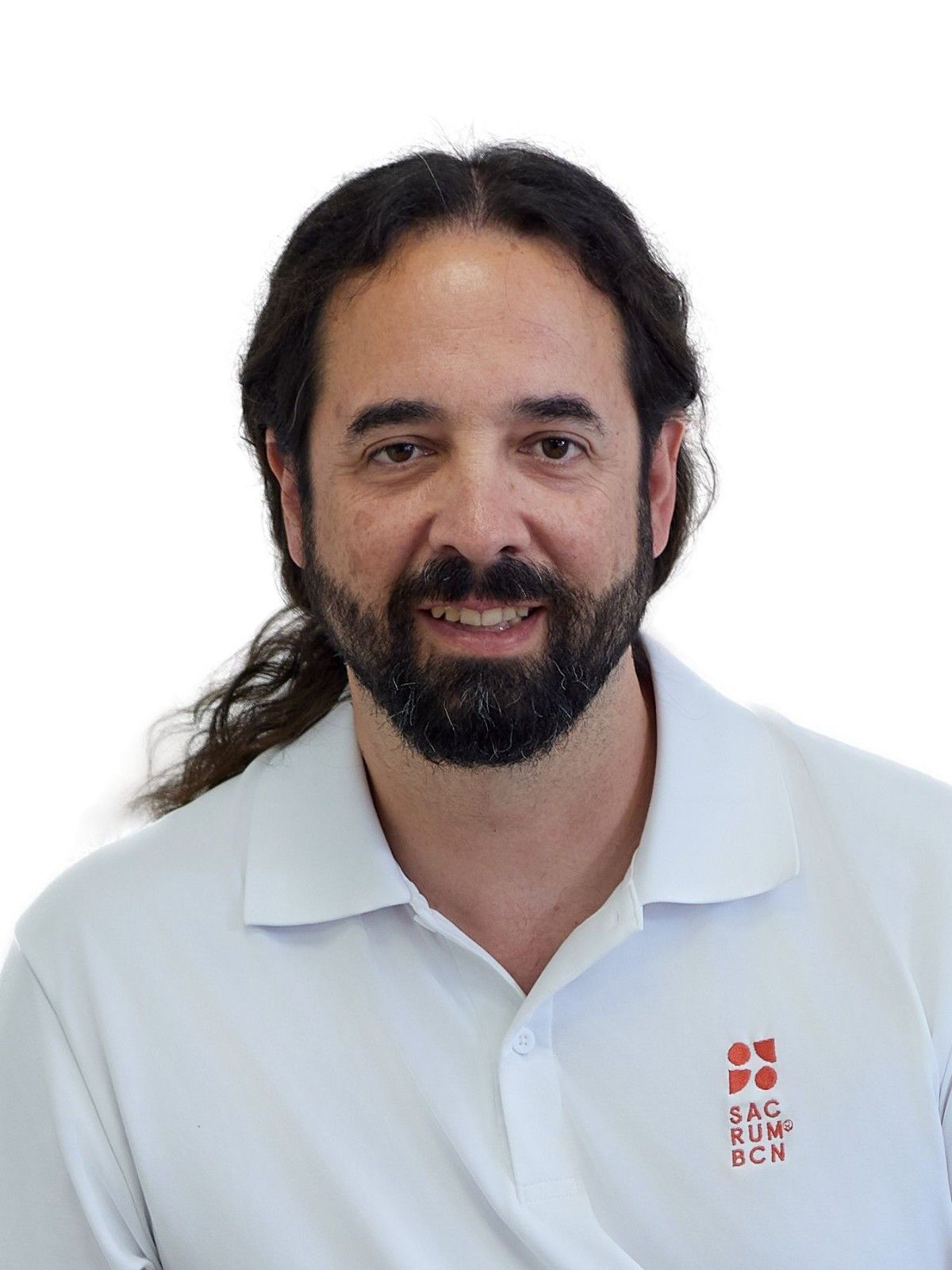 Una persona con barba y cabello oscuro recogido hacia atrás