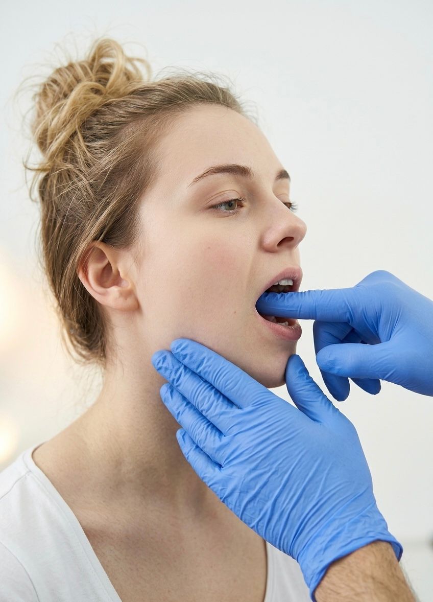 Un profesional sanitario con uniforme azul realiza una exploración física a un paciente en una consulta médica.