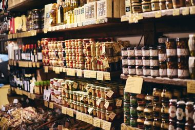 Des étagères remplies de pots et de bouteilles de confitures, de sauces et de condiments.