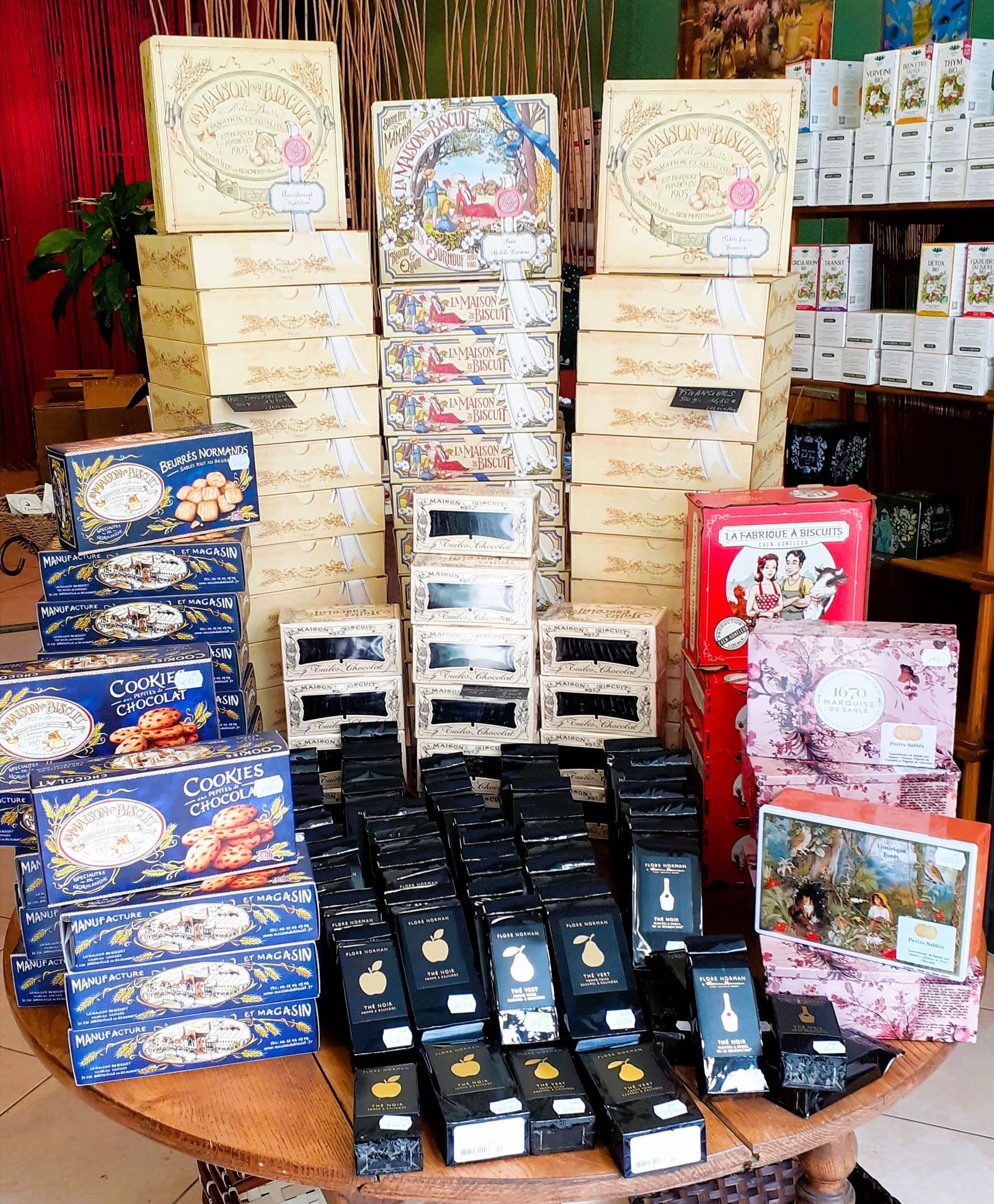 Des articles cadeaux emballés et des cartes assorties sont présentés sur une table dans une boutique colorée.