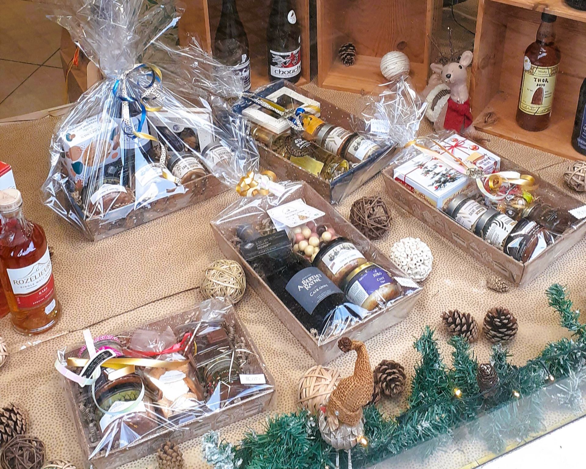 Paniers cadeaux de produits alimentaires et de boissons, présentés sur une étagère en bois.