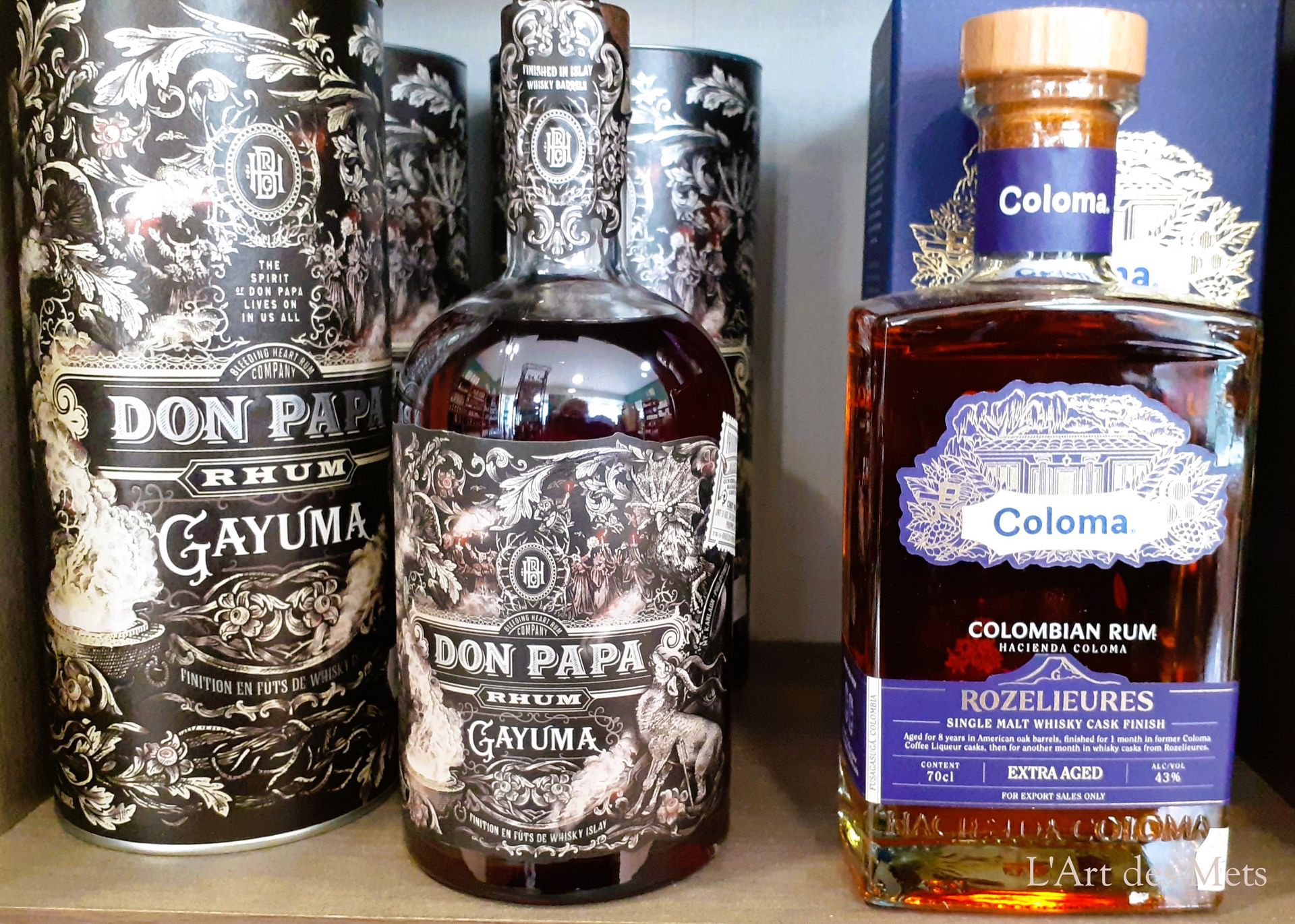 Trois bouteilles d'alcool sur une étagère, dont des étiquettes Don Papa et rhum Coloma.