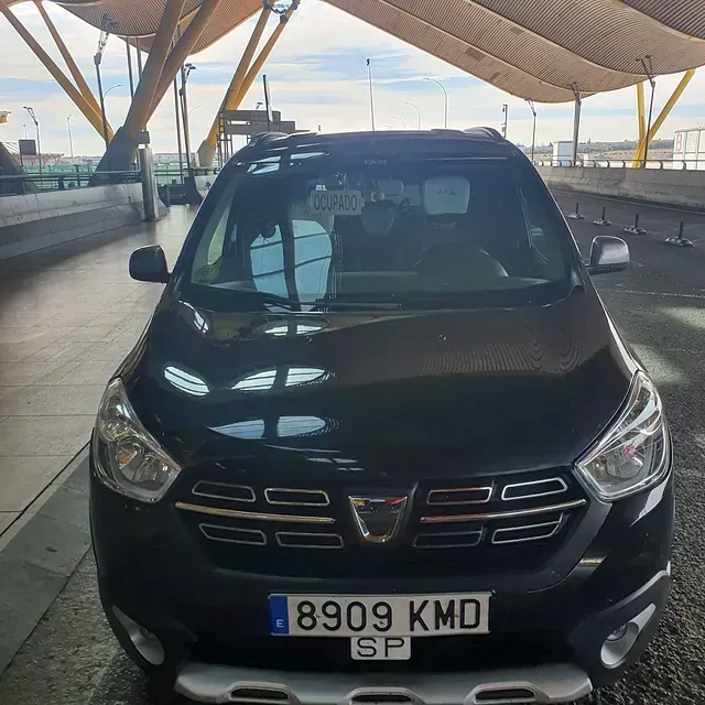 Dacia negro aparcado frente a un edificio moderno. Matrícula española y en buen estado.