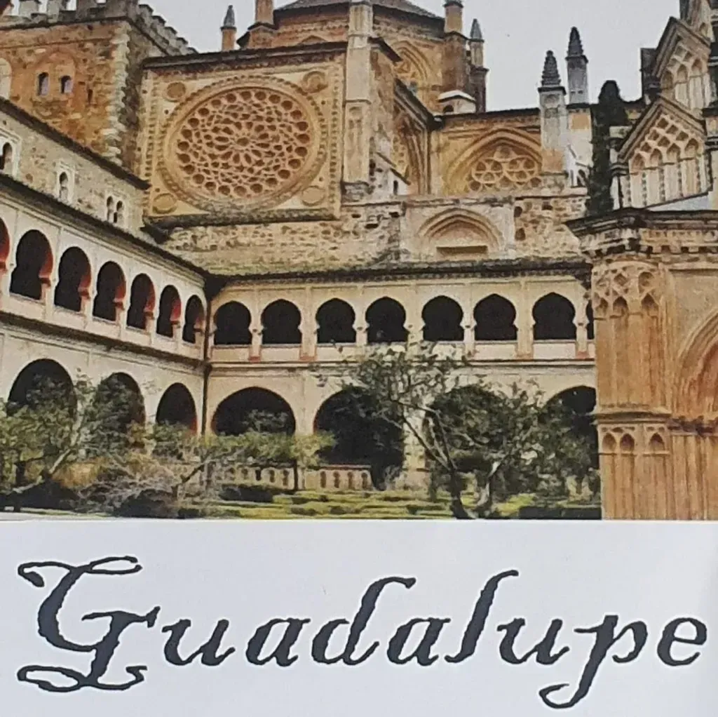 Vista del patio del Monasterio de Guadalupe, con pasillos arqueados, rosetón y la palabra 