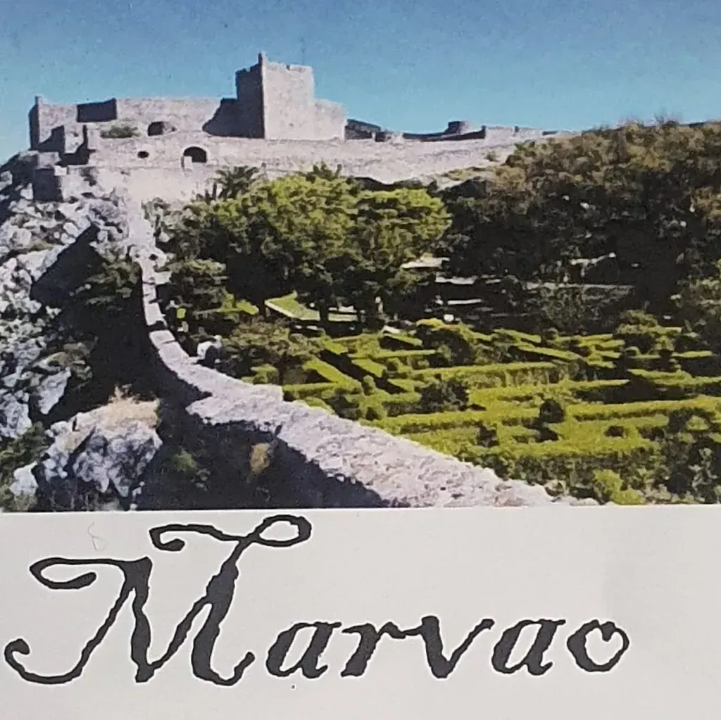 Un castillo de piedra en la cima de una colina con campos en terrazas al pie. La palabra 