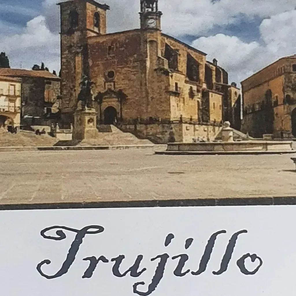 Vista de Trujillo, España, que muestra una gran iglesia con una plaza y una fuente en primer plano. El nombre del pueblo está escrito debajo.