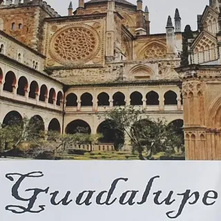 Exterior del Monasterio de Guadalupe en España. Arquitectura de piedra con arcos, un rosetón y la palabra 