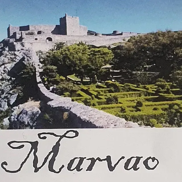 Vista del castillo de Marvão en Portugal, con muros de piedra, jardines y el castillo encaramado en la cima de una colina.