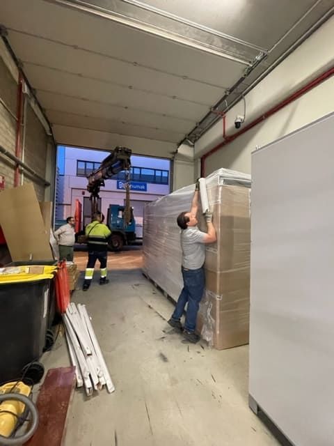 Un hombre está abriendo una caja grande en un almacén.