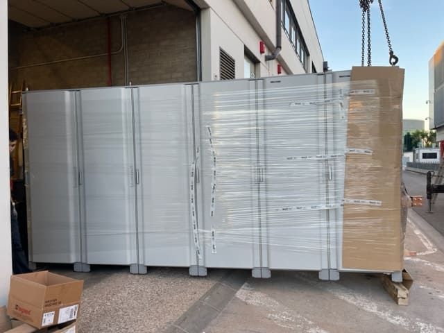 Una gran caja blanca está siendo levantada por una grúa