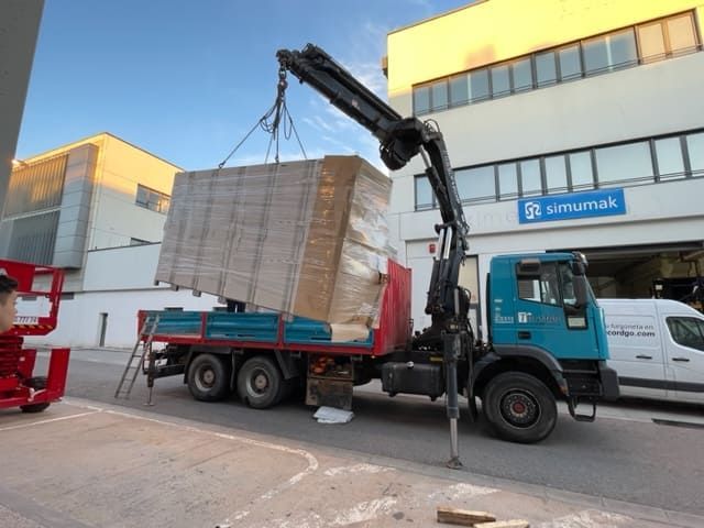 Una grúa está levantando una caja grande desde la parte trasera de un camión.
