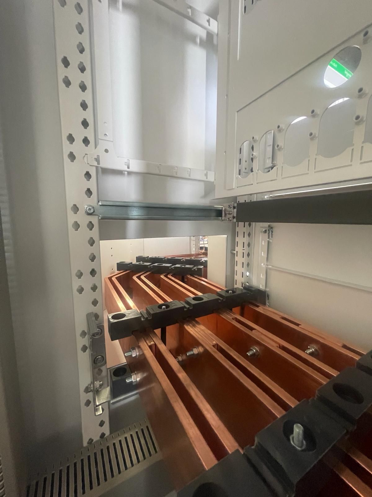 Una fila de cables de cobre que pasan a través de un gabinete de acero inoxidable.