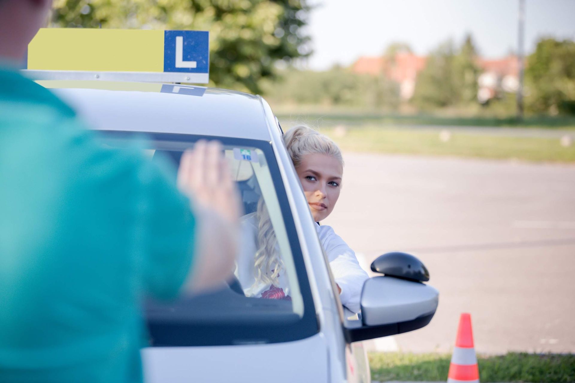 Una mujer está sentada en un coche hablando con un instructor de manejo.