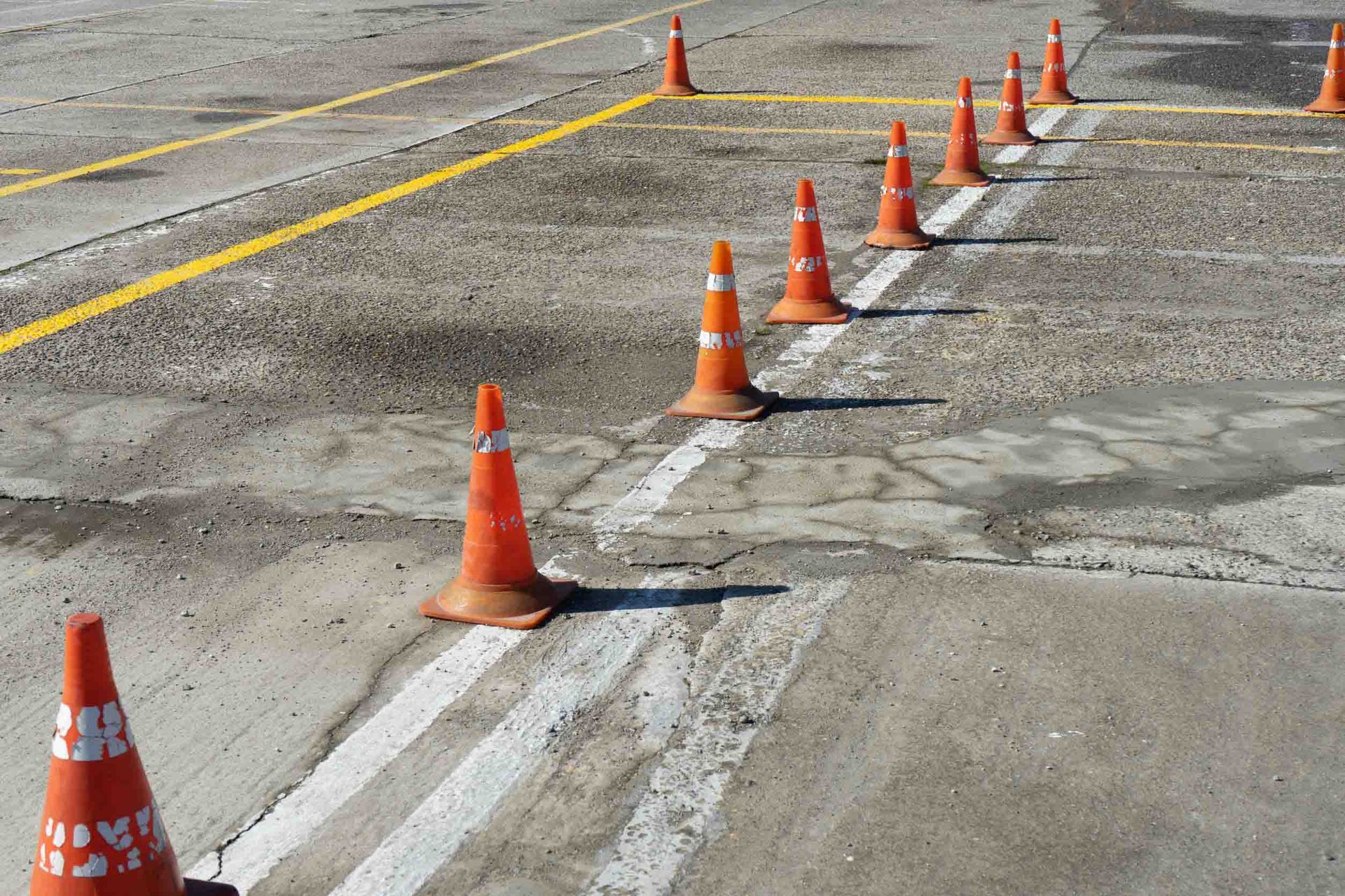 Una fila de conos de tráfico naranjas en un estacionamiento