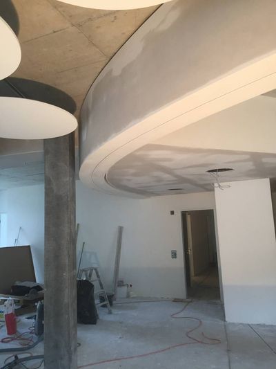 Unfertiger Innenraum mit gewölbter Decke, freiliegenden Betonwänden und auf dem Boden verstreuten Baumaterialien.