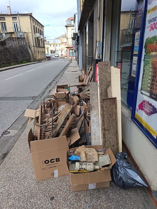 Des cartons et des débris laissés sur un trottoir.