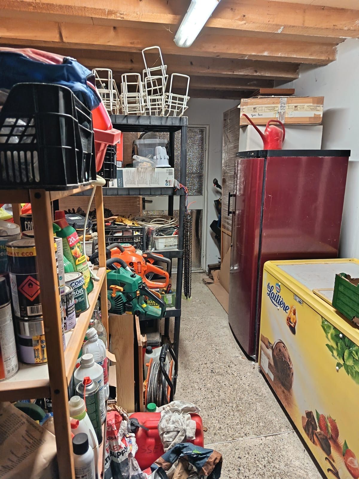 Débarras encombré avec des étagères, des objets empilés et une armoire.