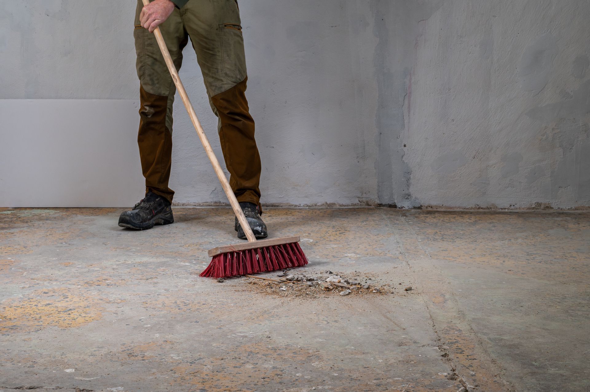 Un ouvrier qui balaye des résidus de travaux.