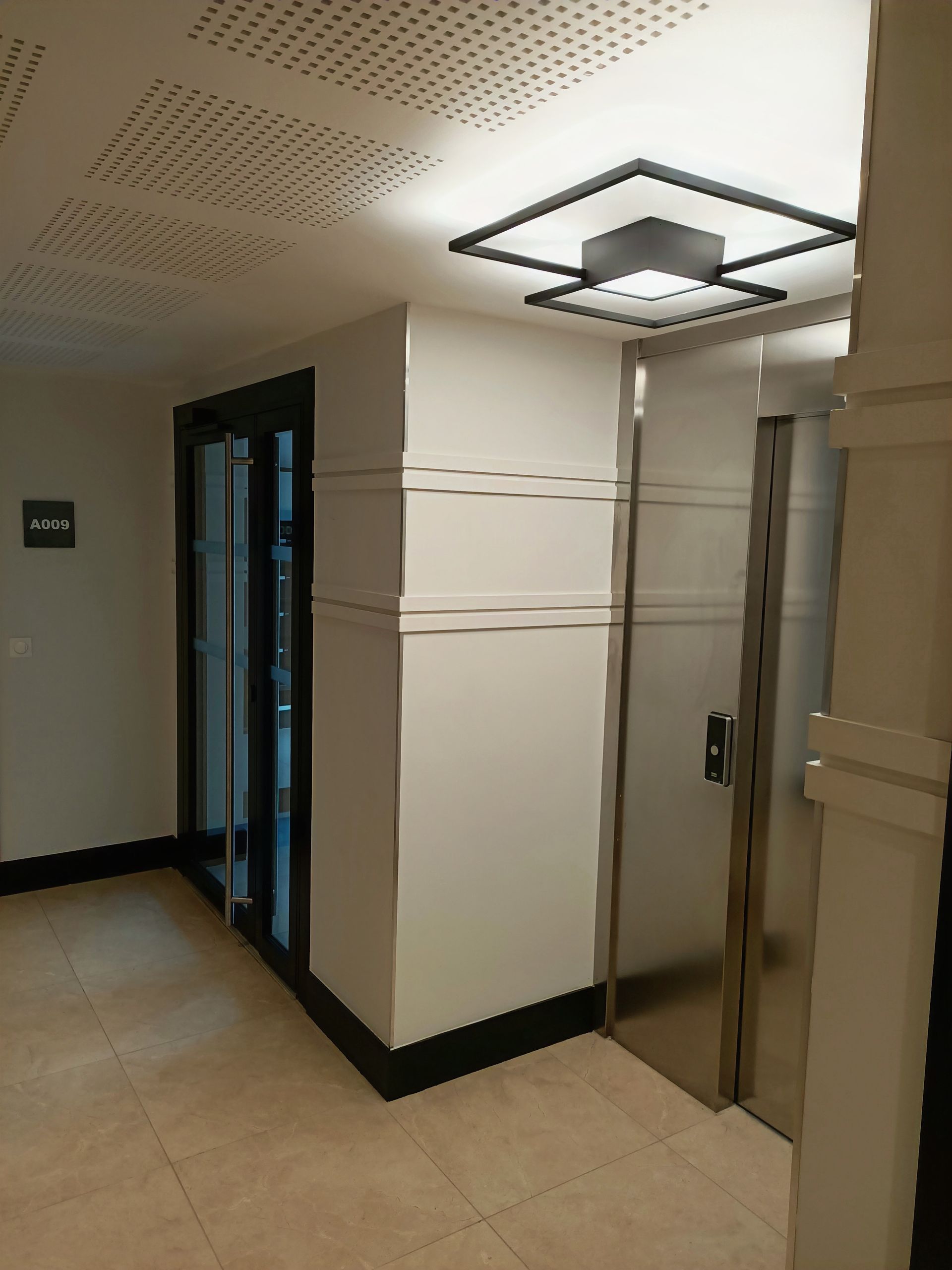 Un couloir avec une porte en acier inoxydable et une lumière au plafond