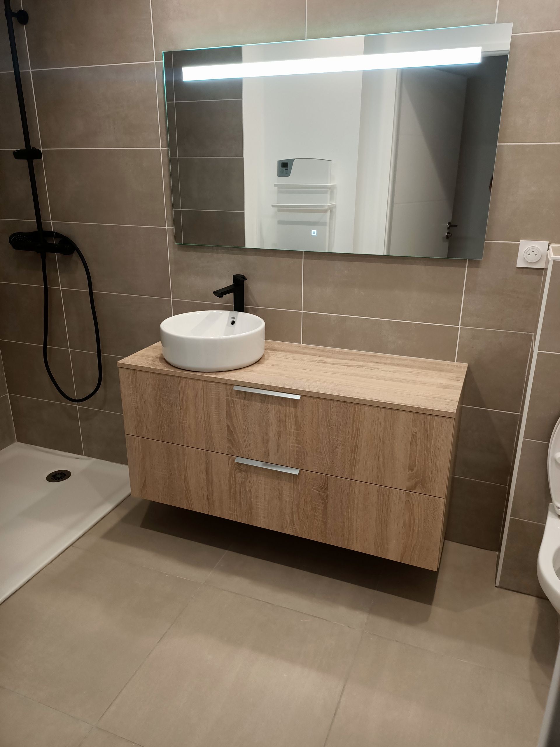 Une salle de bain avec lavabo, miroir et douche.