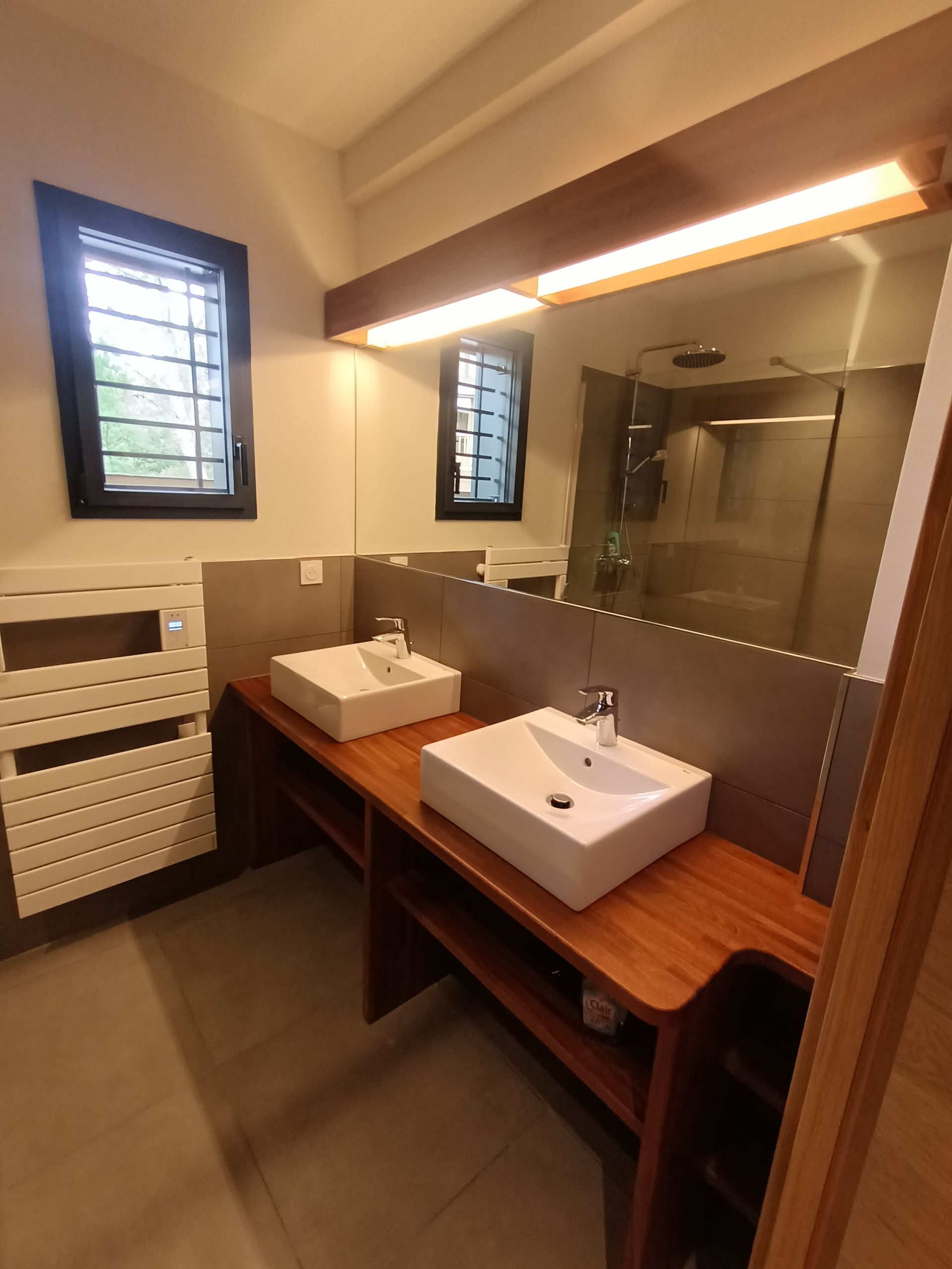 Une salle de bain avec deux lavabos et un grand miroir