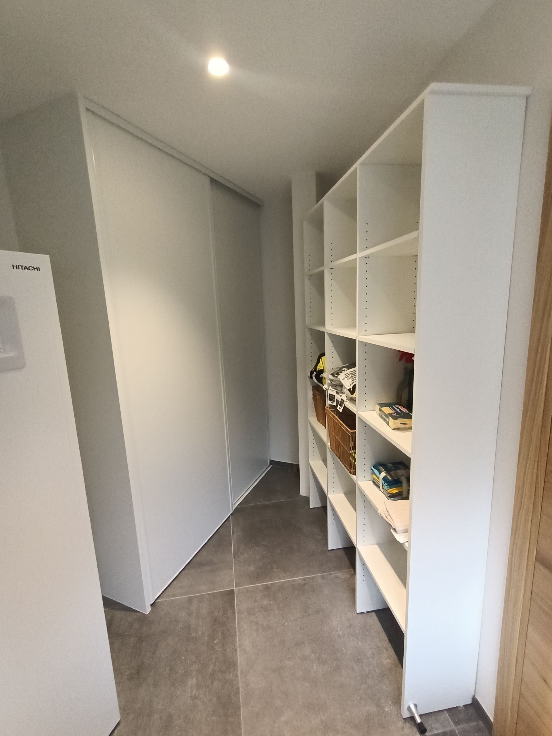 Un couloir avec beaucoup d'étagères et un réfrigérateur.