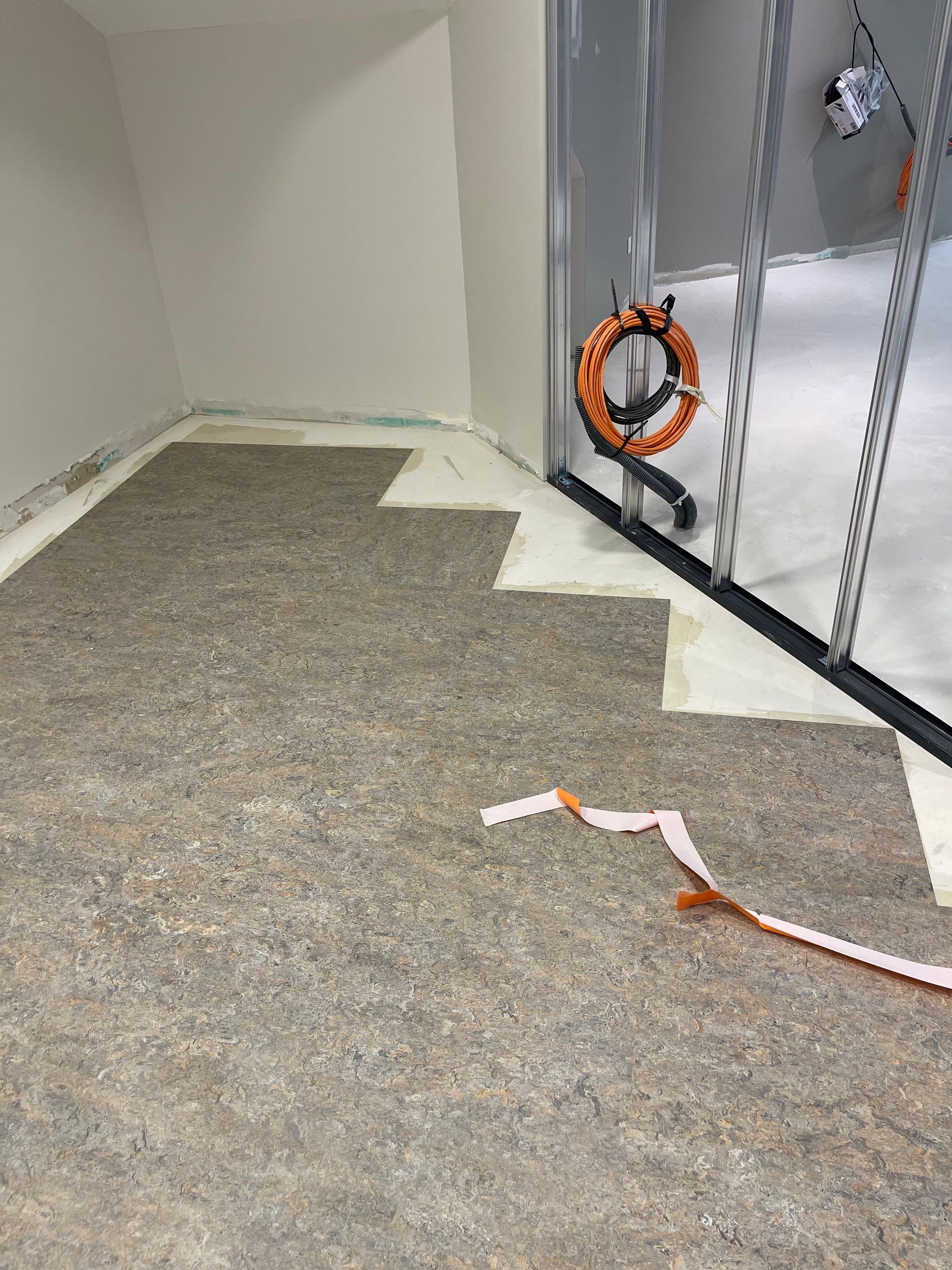 Installation d'une sous-couche de moquette dans une pièce aux murs gris clair et à l'encadrement de porte argenté.