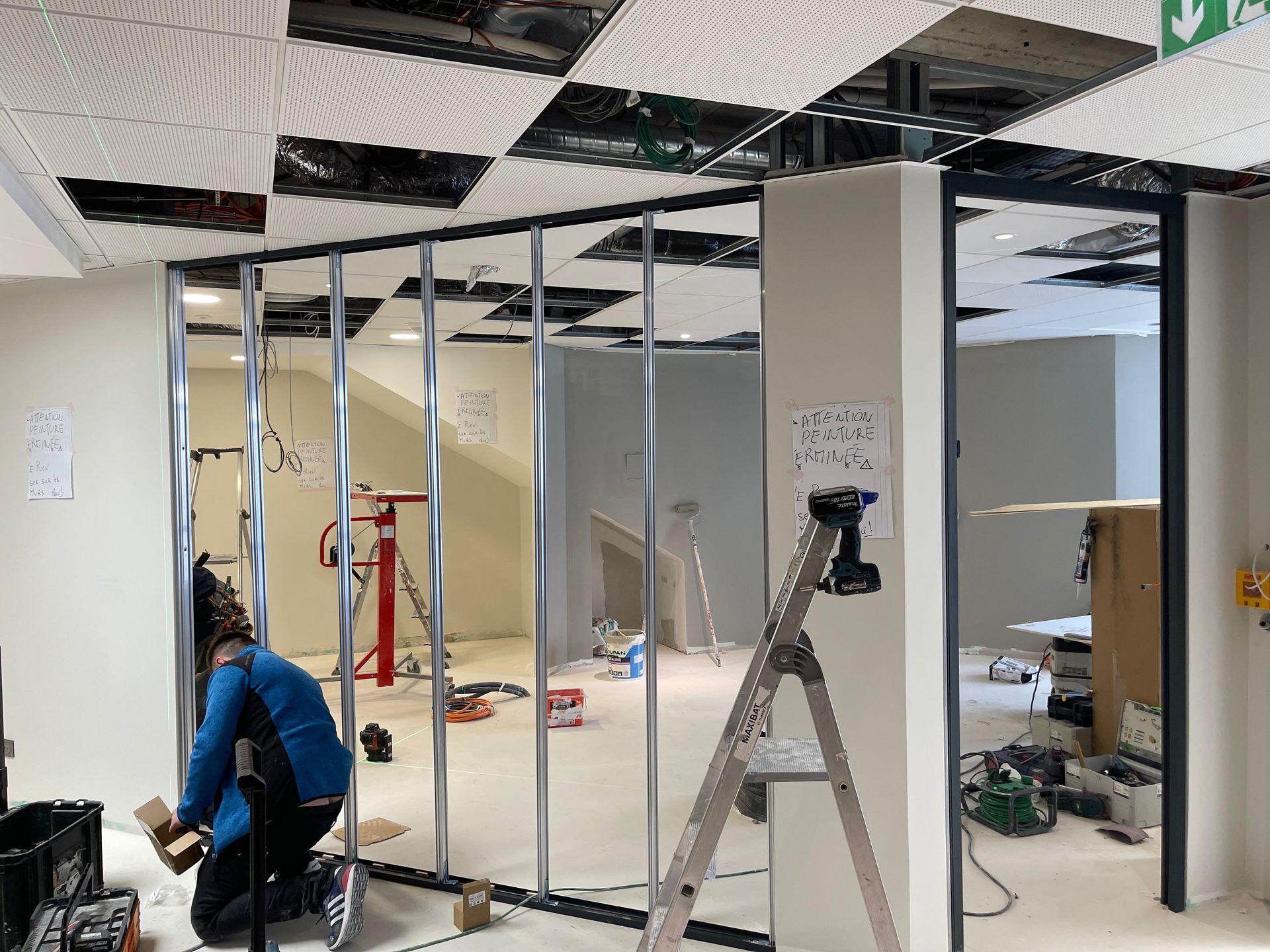 Un ouvrier du bâtiment installe des montants métalliques pour une cloison intérieure.