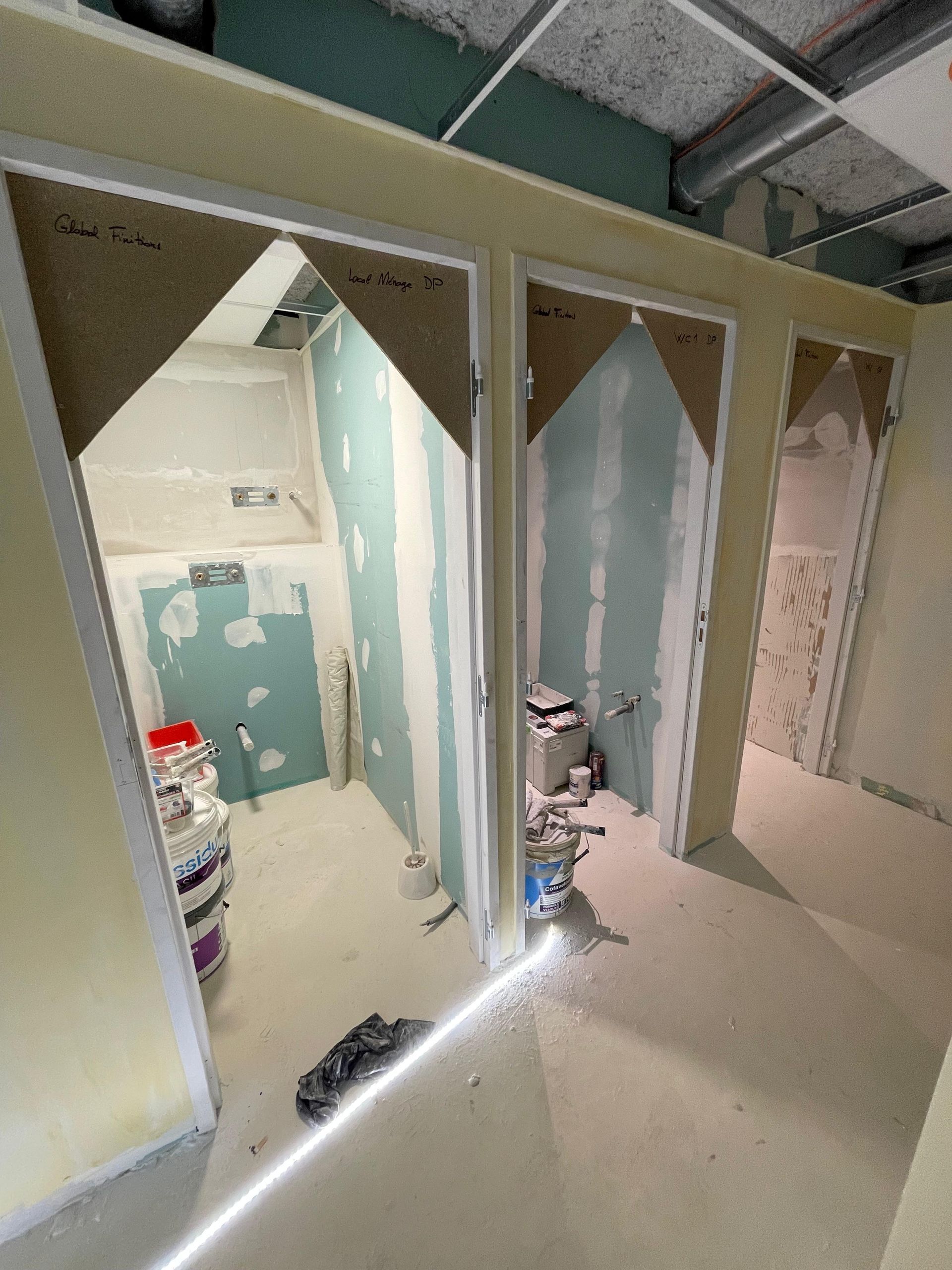 Chantier avec portes. Cloisons sèches et outils visibles. Niveau laser traçant une ligne lumineuse.