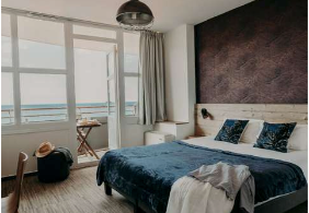 Une chambre d'hôtel avec un grand lit et un balcon donnant sur l'océan.