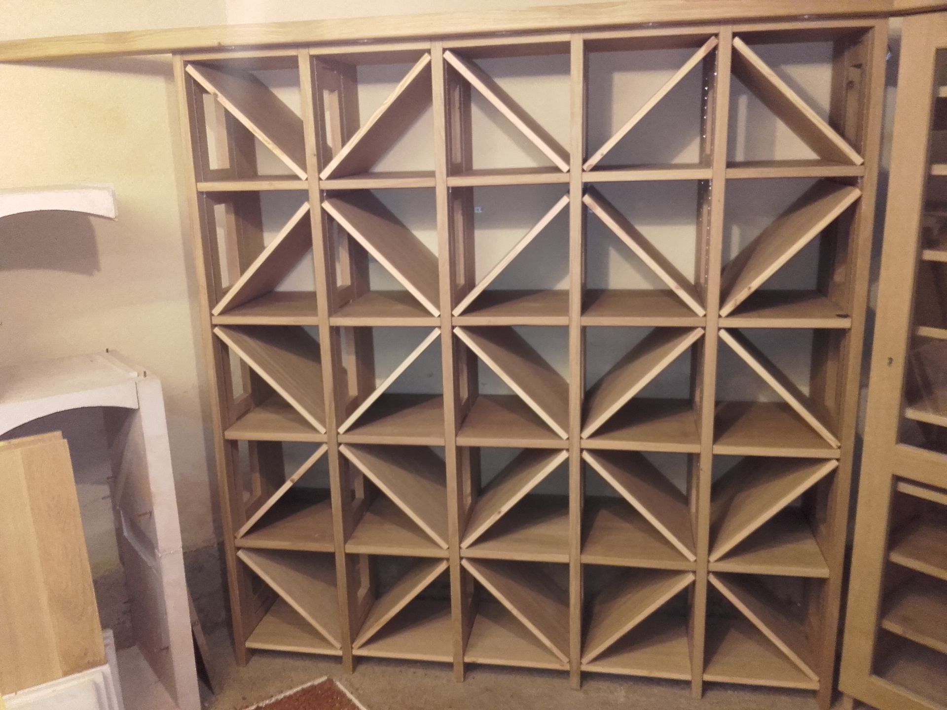 Une étagère en bois avec des triangles dessus dans une pièce