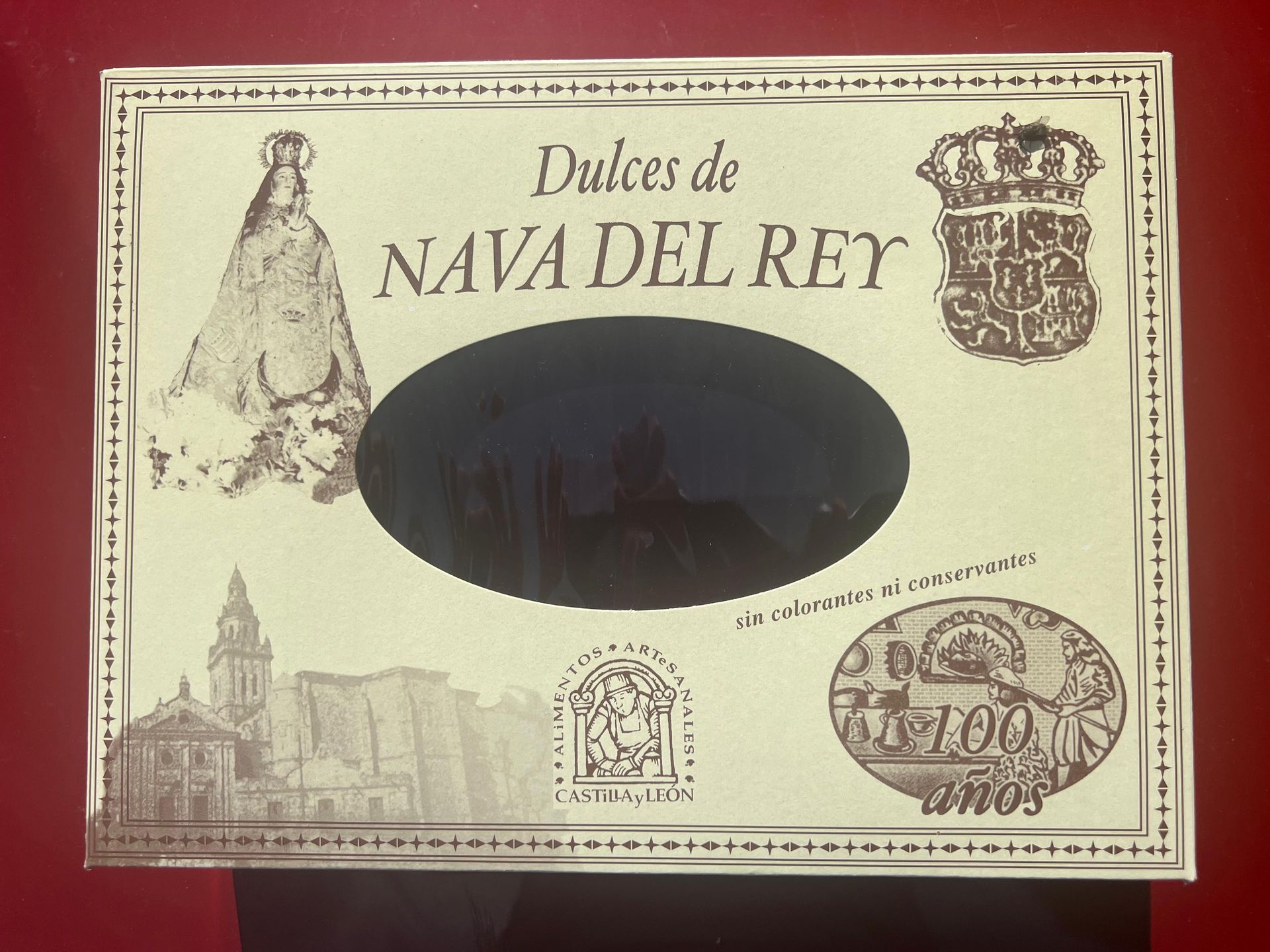 Caja de dulces de Nava del Rey, con ilustraciones de una iglesia, escudo real y una figura.