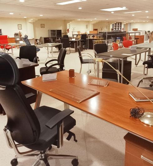 Sala de exposición de oficinas con escritorios, sillas y monitores de ordenador en un espacio de trabajo abierto y luminoso.
