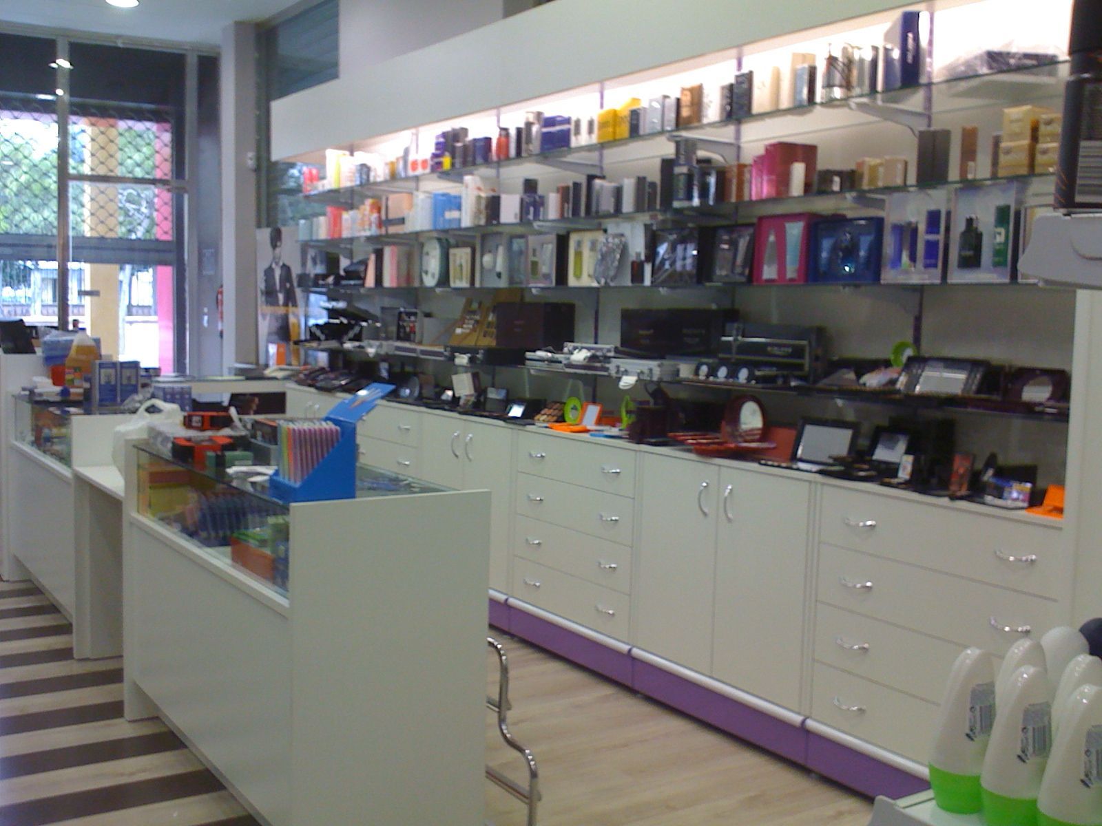 Interior luminoso del salón con estantes de productos para el cabello, armarios blancos y alfombras a rayas en el suelo.
