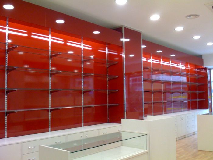 Interior vacío de una tienda con estanterías rojas brillantes en la pared y mostradores blancos