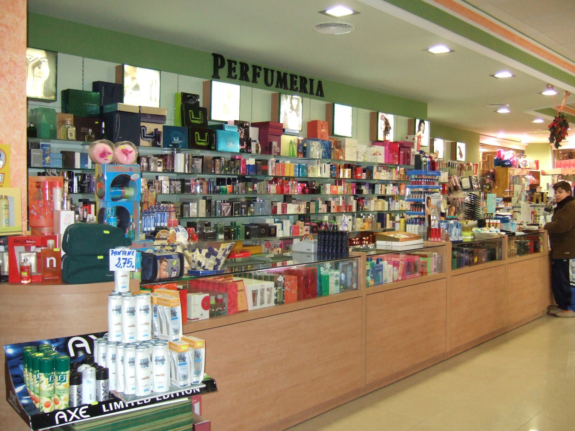 Mostrador de perfumería con estantes de perfumes y cosméticos en el interior de una tienda muy iluminada.