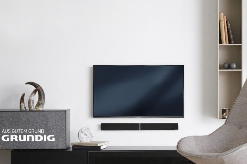 Ein Wohnzimmer mit einem Fernseher an der Wand und einem Stuhl