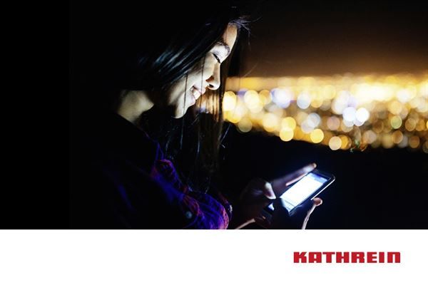 Eine Frau schaut im Dunkeln auf ihr Handy.