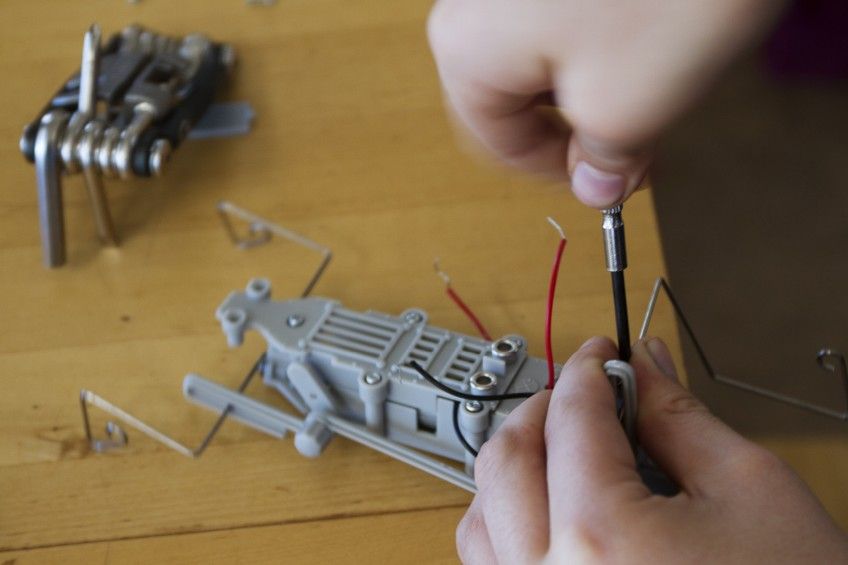 Eine Person arbeitet mit einem Schraubenzieher an einem Spielzeug