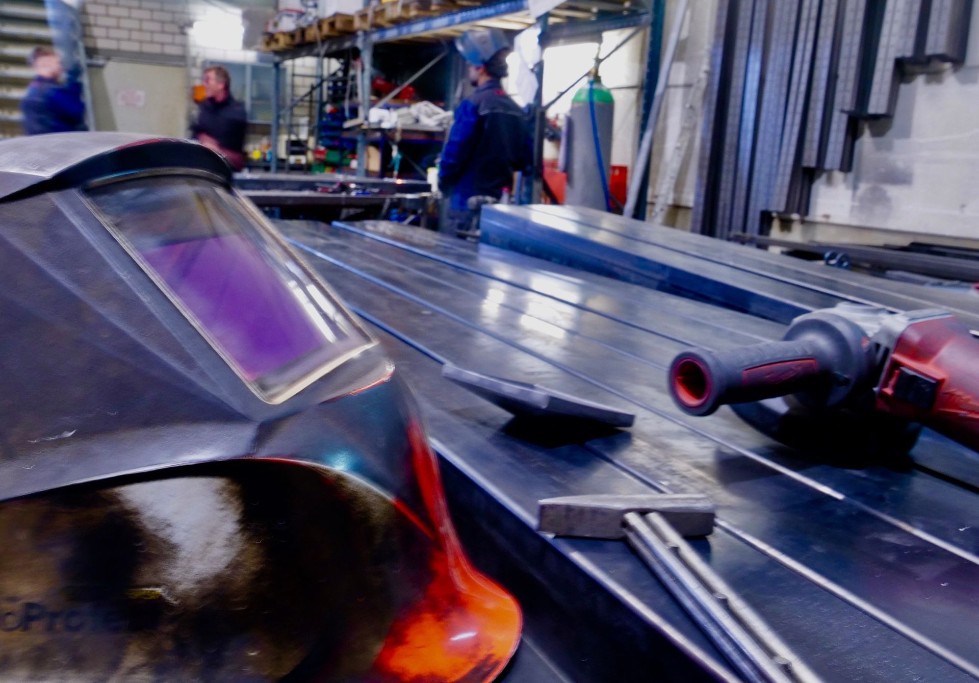 Ein Schweißhelm und eine Schleifmaschine liegen auf einem Tisch in einer Fabrik.
