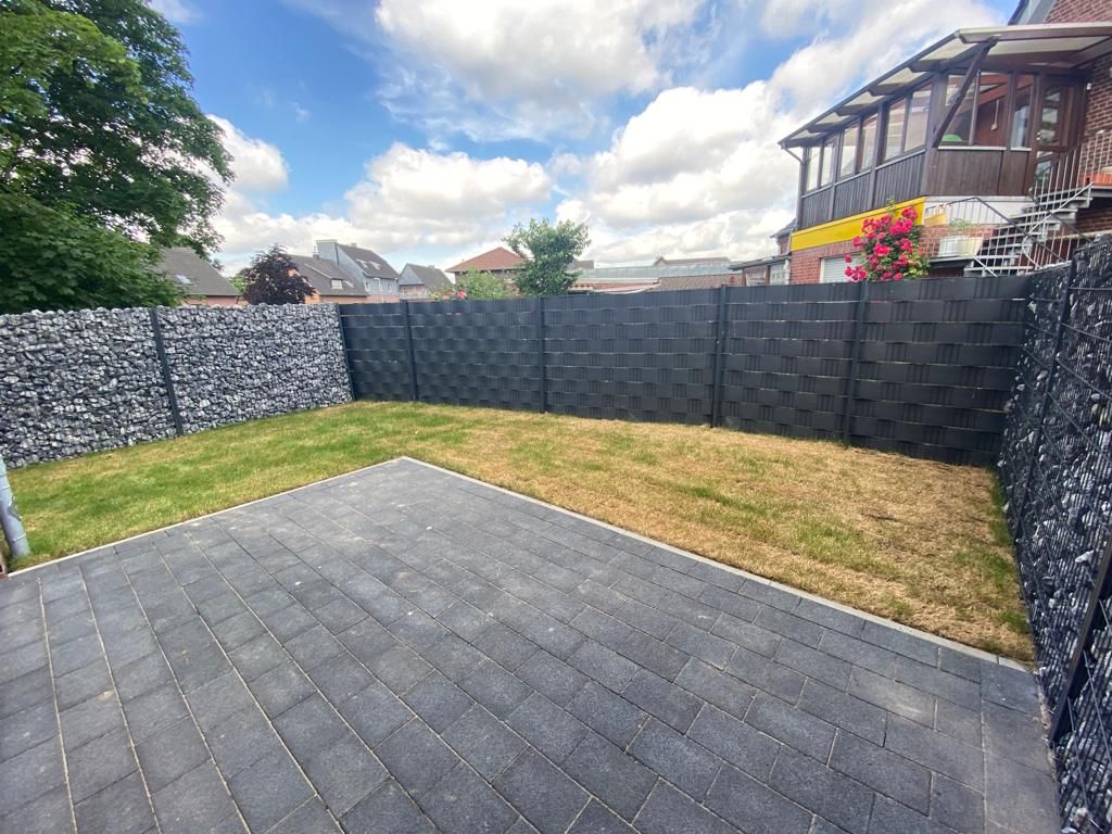 Ein Hinterhof mit einem Zaun und einem gemauerten Gehweg.