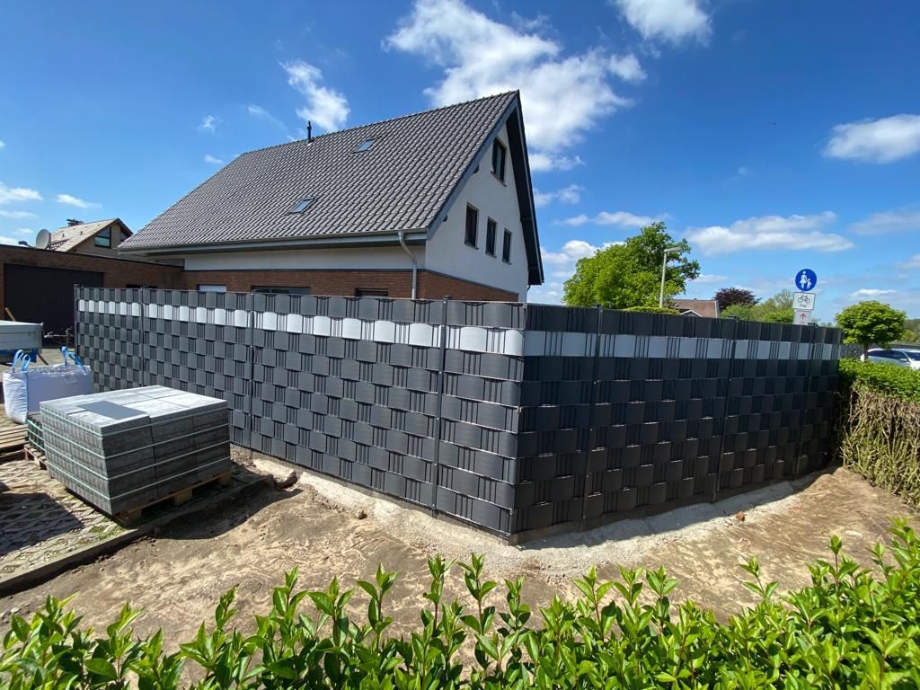 Vor einem Haus wird ein Zaun gebaut.