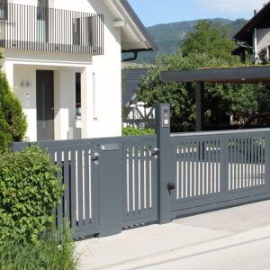 Ein Haus mit Zaun und davor einem Carport.