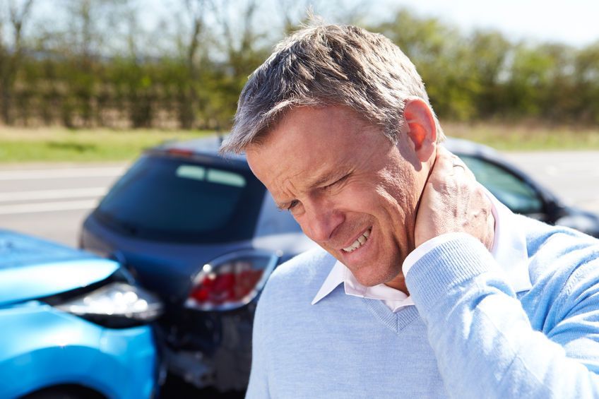 Un hombre se sostiene el cuello con dolor después de un accidente automovilístico.