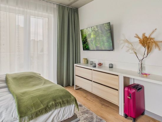 Minimalistyczna sypialnia z zielonym łóżkiem, telewizorem zamontowanym na ścianie