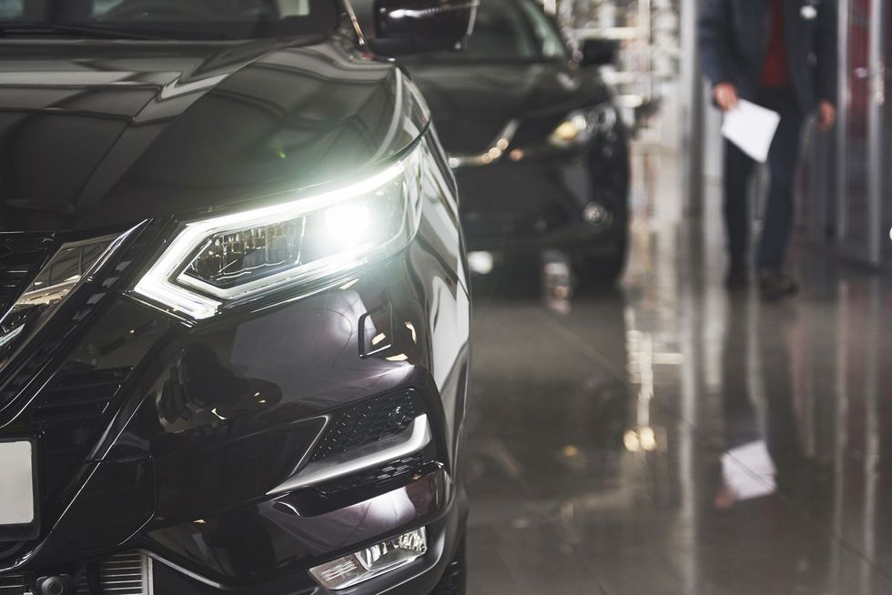 Zbliżenie na czarny luksusowy SUV z jasnymi reflektorami w salonie wystawowym lub garażu parkingowym
